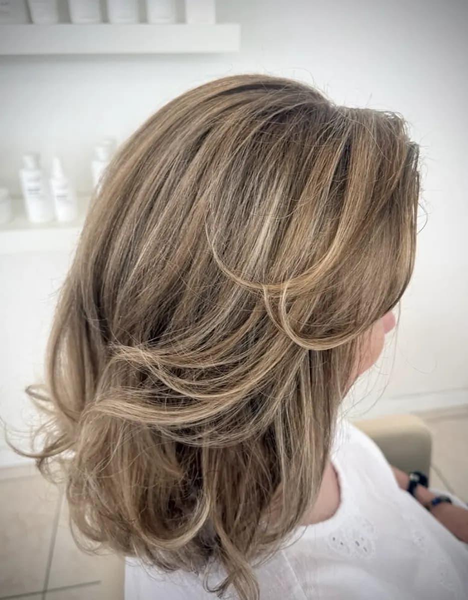 Mittellanger Stufenschnitt in Dunkelblond mit hellen Spitzen.